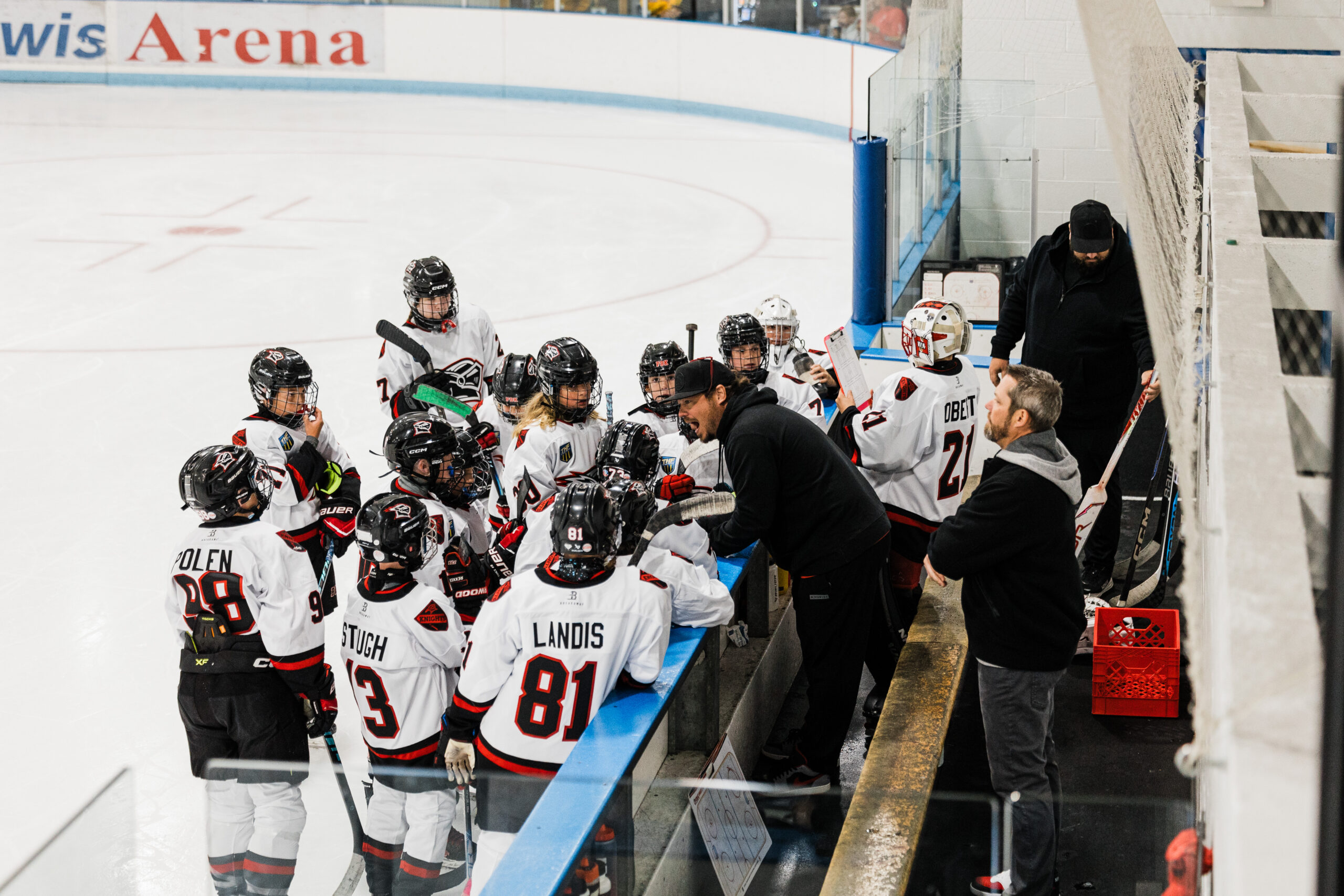 Jake Javitt giving instruction to his youth hockey team huddled along the boards